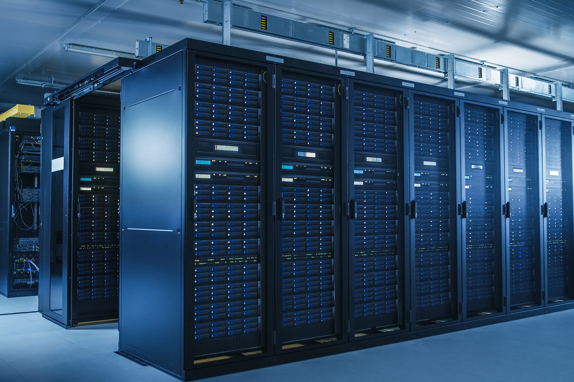  A large room filled with tall black server racks containing multiple blinking lights and hard drives.