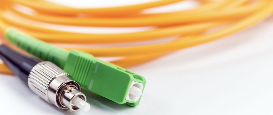 Fiber optic cable with green connector and yellow cable for networking.