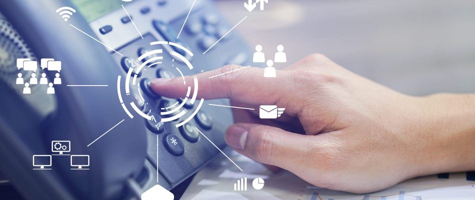 Hand pressing a button on a VoIP phone with digital communication icons.