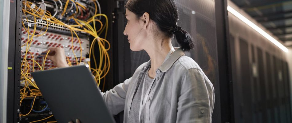 Technician working on network cabling in a data center server room.