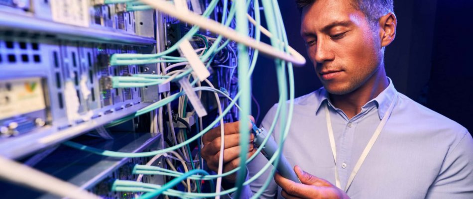 Technician inspecting network cables in a server room.