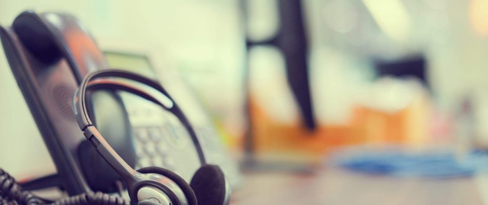 Office desk with telephony equipment and headset for business communication.