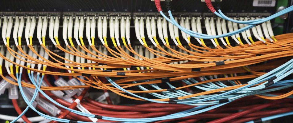 Data center structured cabling with organized fiber optic and Ethernet cables.
