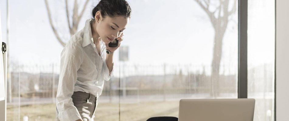 Businesswoman on phone with laptop in modern office setting.