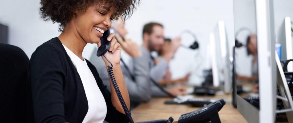 Woman smiling on phone at work in a call center environment.